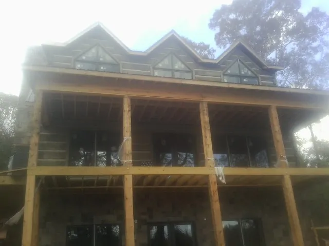 Dormers and porch framing on a large log home under construction — Roof Coating work by our crew in East Pembroke