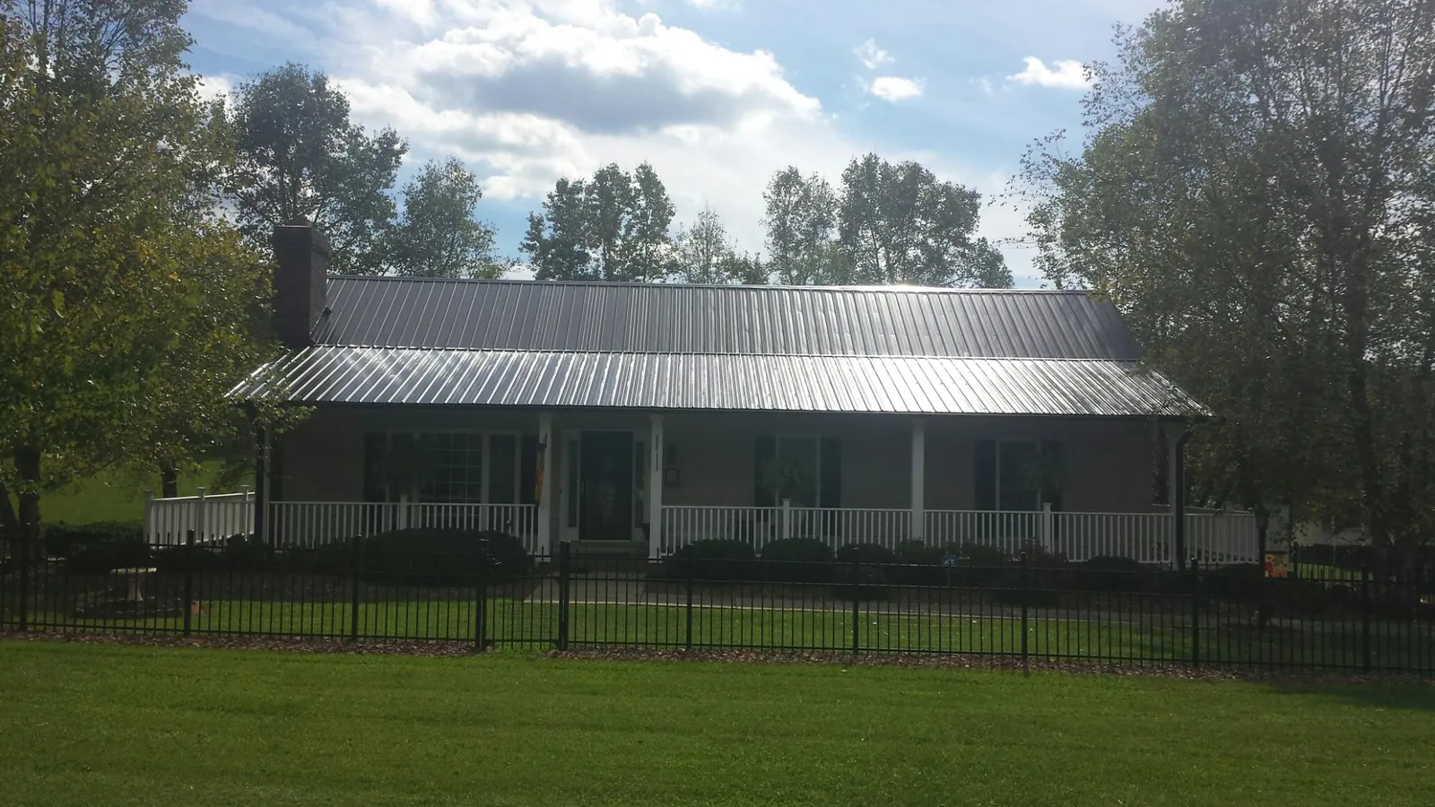 Gray metal roof on a brick ranch with a full width front porch — Gutter Guard Installation work by our crew in East Pembroke