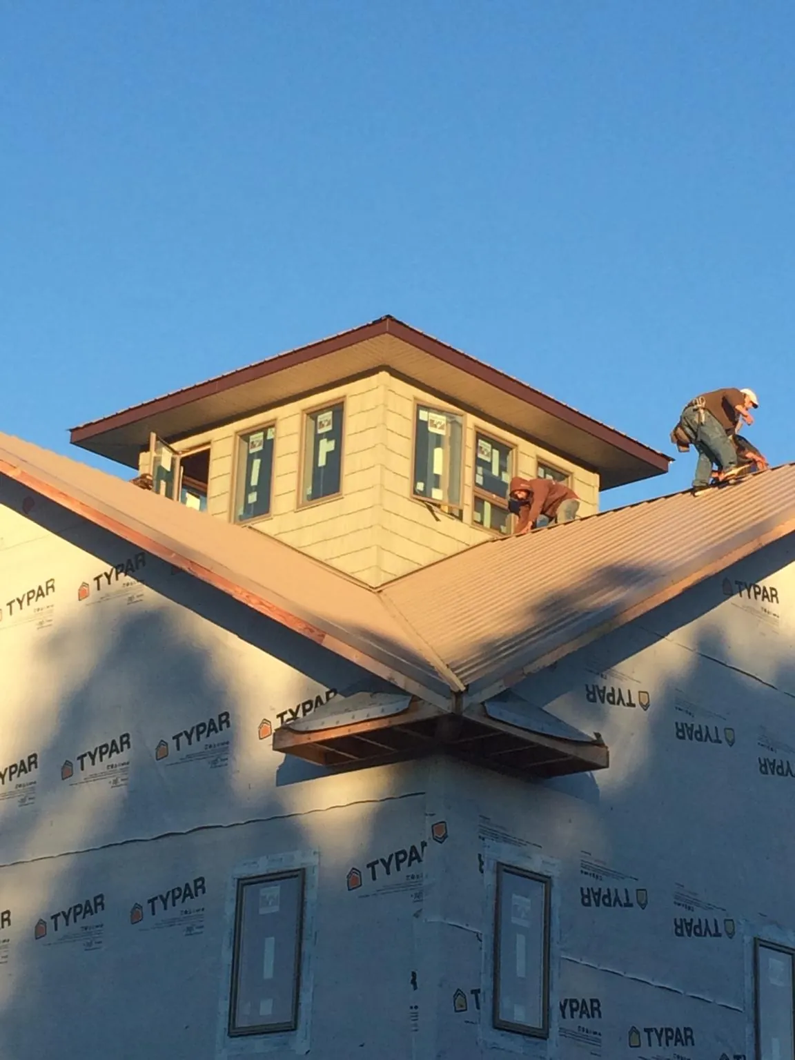 Roofers working around a rooftop cupola on a new metal roof at sunset — Roof Waterproofing in East Pembroke by Roofing Brothers